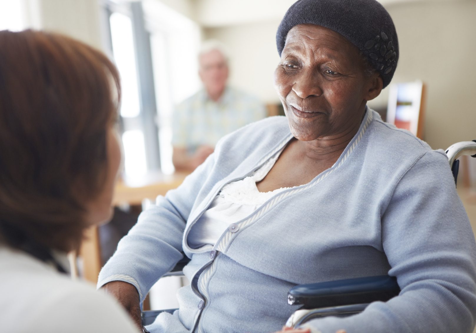 A caregiver talking to a wheelchair-bound patient